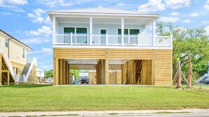 Une maison à deux étages avec un balcon, un garage fermé et une cour gazonnée.