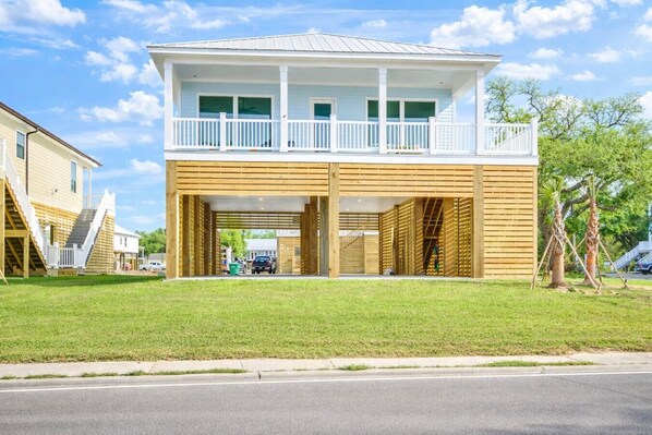 Une maison à deux étages avec un balcon, un garage fermé et une cour gazonnée.