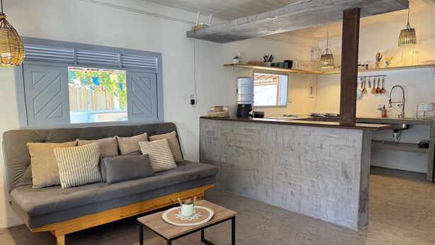 A modern living space with a sofa, coffee table, and a kitchen area with a bar counter. - Oceana Suites Vila Cajarana (Tibau do Sul)