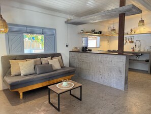 Un espacio habitable moderno con sofá, mesa de centro y una cocina con barra.