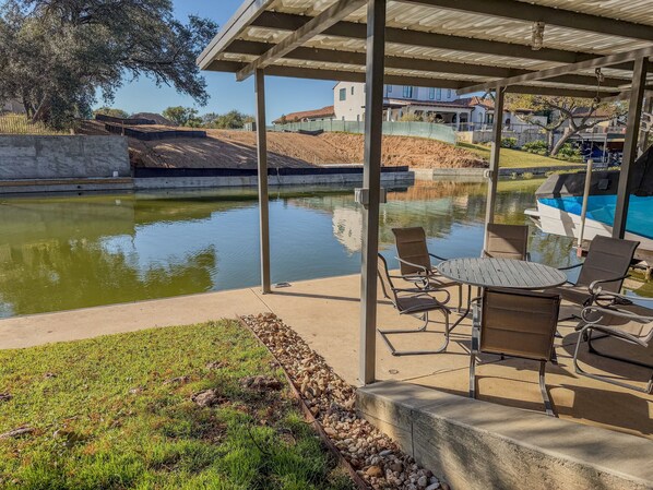 Un patio couvert avec une piscine, des sièges d’extérieur et une vue sur un quartier résidentiel.