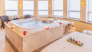A spa room with a large hot tub, seating area, and a massage table. - Cozy 1-bedroom luxe hotel suite in magnificent and fun Cabo San Lucas. (Cabo San Lucas)