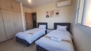 Habitación de hotel con dos camas, un armario y un equipo de aire acondicionado.