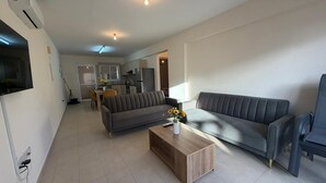Una sala de estar moderna con un sofá gris, una mesa de centro de madera y un televisor montado en la pared.