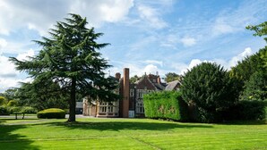 Un grand bâtiment historique doté d’une pelouse bien entretenue et de grands arbres.