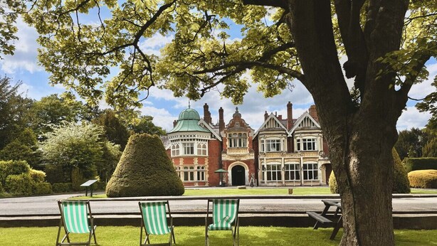 Il s’agit d’un grand bâtiment historique, doté d’un imposant dôme vert et d’une façade en briques rouges. Devant, on trouve une pelouse bien entretenue, agrémentée de trois chaises de jardin à rayures et d’une table de pique-nique.