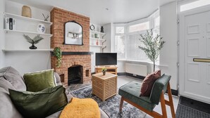 Un salon avec une cheminée en briques, un téléviseur, un canapé et une petite table.