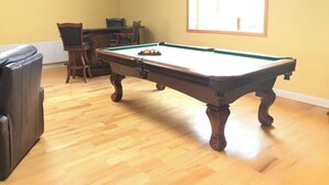 A pool table in a room with wooden flooring, a leather couch, and a window with blinds. - Delightful 4-bedroom house in peaceful Connemara Countryside (Moycullen Galway)