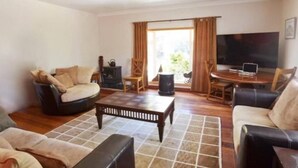 A living room with a sofa, armchair, coffee table, and a TV. - Delightful 4-bedroom house in peaceful Connemara Countryside (Moycullen Galway)