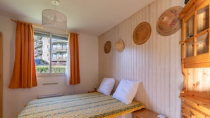A bedroom with a bed, a wooden cabinet, and a window with curtains.