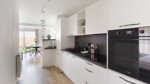 A modern kitchen with white cabinetry, a black countertop, and a Whirlpool oven. - Couleur Sable - 1km de la Plage (Dinard)