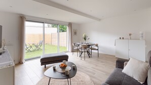 A modern living room with a sofa, coffee table, and dining area. - Couleur Sable - 1km de la Plage (Dinard)