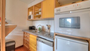 Eine kompakte Küche mit Geschirrspüler, Kühlschrank und Mikrowelle.