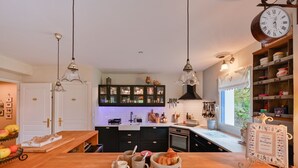 Una cocina con armarios oscuros, encimera de madera, lámparas colgantes y una ventana que ofrece vistas a la vegetación.