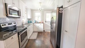 Une cuisine moderne avec des meubles blancs, des appareils électroménagers en acier inoxydable et un plancher en bois.