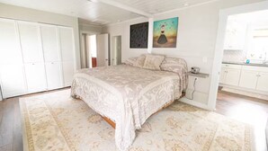 Une chambre avec un grand lit, une armoire et un tableau accroché au mur.