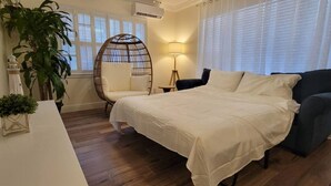 Une chambre à coucher avec un lit, une chaise, une table et une plante en pot.