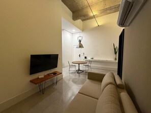 A modern living room with a flat-screen TV, a wooden side table, a sofa, a dining table with chairs, and a pendant light. - Noroeste design comfort and charm (Brasília)