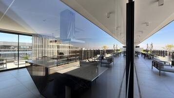 Eine moderne Dachterrasse mit Glasfassade, Außenbestuhlung und Blick auf die Stadtlandschaft.