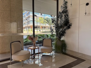 A modern lobby with two chairs, a vase with dried flowers, and a large potted plant. - Noroeste design comfort and charm (Brasília)