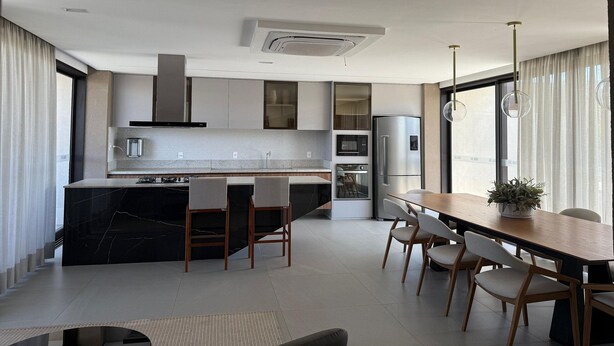 A modern kitchen with a central island, built-in appliances, and a dining area with a wooden table and chairs. - Noroeste design comfort and charm (Brasília)