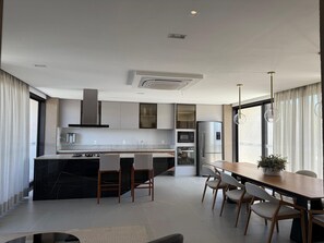 A modern kitchen with a central island, built-in appliances, and a dining area with a wooden table and chairs. - Noroeste design comfort and charm (Brasília)