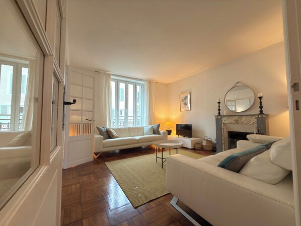 A living room with a sofa, a television, a fireplace, and a large window.