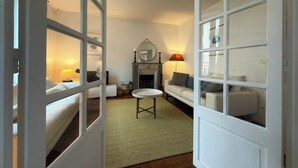 Een kamer met een open haard, een bank, een kleintje tafeltje en een spiegel aan de muur.