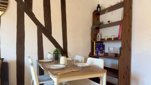 Ein Essbereich mit einem Holztisch, weißen Stühlen und einem Bücherregal mit Büchern und Dekoration.