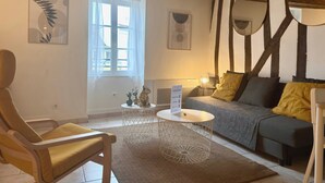 Ein Zimmer mit einer Couch, einem Sessel, einem runden Couchtisch und Bildern an den Wänden.