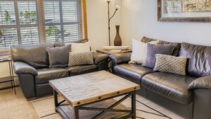 Un salon moderne avec des canapés en cuir, une table basse en bois et un lampadaire.