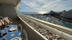 A balcony with a table set for two, overlooking a marina with boats and buildings. - 06DJ - Apartment with sea view for 4 people - terrace (Villeneuve-Loubet)
