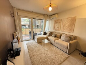 A modern living room with a beige sofa, a glass coffee table, and a large window with curtains. - Cozy apartment in the heart of Nice (Nice)