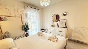 Une chambre moderne avec un grand lit, une commode, un miroir et une plante en pot.