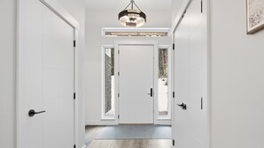Un pasillo con puertas blancas, piso de madera y una lámpara en el techo.