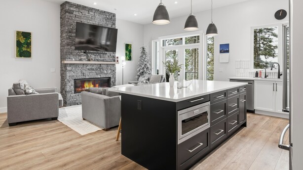Una cocina moderna con una isla grande, una chimenea de piedra e iluminación colgante.