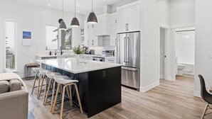 Una cocina moderna con una isla grande, electrodomésticos de acero inoxidable e iluminación colgante.