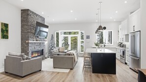 Una cocina moderna con una isla central, electrodomésticos integrados y una pared decorativa de piedra.