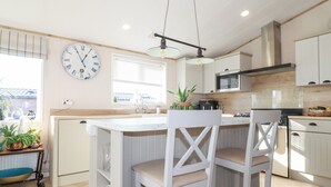Una cocina moderna con una isla central, armarios blancos y un reloj de pared grande.