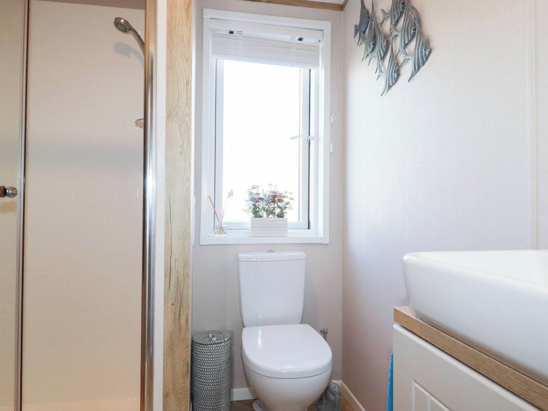 Een kleine badkamer met toilet, een raam met plant en een douche.