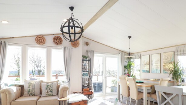 Una sala de estar amplia con un sofá, un comedor con sillas, una mesa y un ventanal con vistas al exterior.