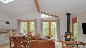 A spacious living area with a wooden dining table, a sofa, and a fireplace. - 2 Streamside (Looe)