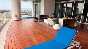 Una terrazza moderna con pavimento in legno e due poltrone blu.