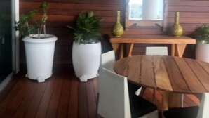 Zona pranzo con tavolo e sedie in legno, circondata da piante in vaso.