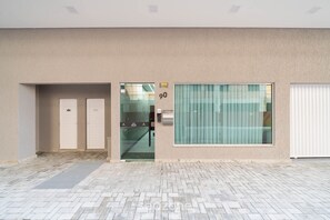 A building entrance with a glass door, a number '90' sign, and a window with blinds. - Apt w/ Barbecue Grill 850 m From the Beach Sem0302 (Itapema)