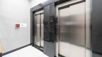 A modern elevator with a control panel and emergency button.