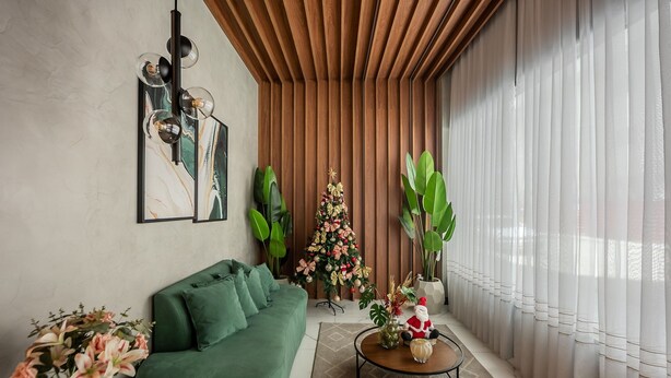 Un saló modern amb un sofà verd, una taula de centre, un arbre de Nadal i una finestra gran amb cortines translúcides.