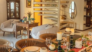 Een eetruimte met een spiltrap, rieten stoelen en een gedekte tafel.