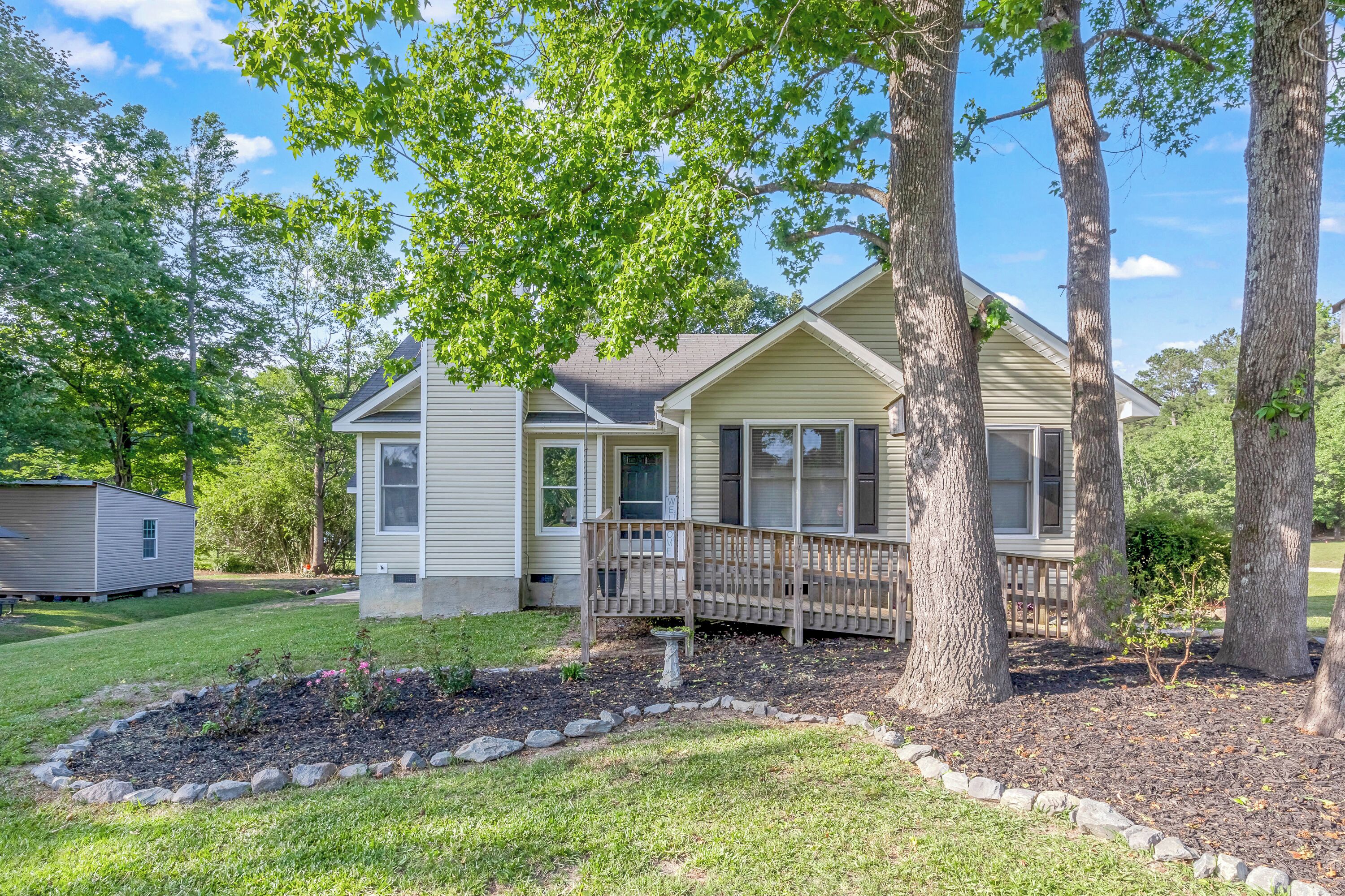 A single-story house with a front porch, surrounded by trees and a well-maintained lawn.