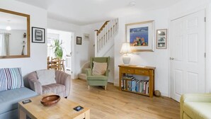 En stue med sofa, lænestole, sofabord, reoler, lampe og trappe.
